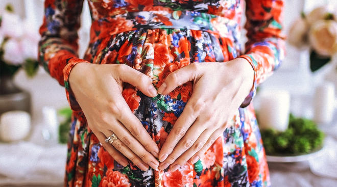 pregnant woman in floral dress touching her belly