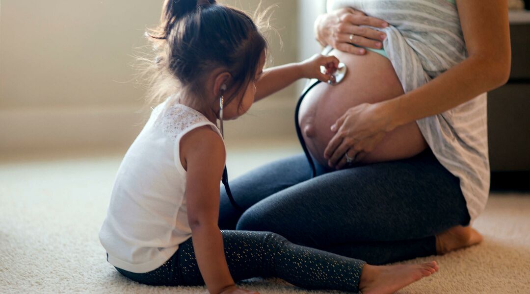 daughter playing doctor with her pregnant mom